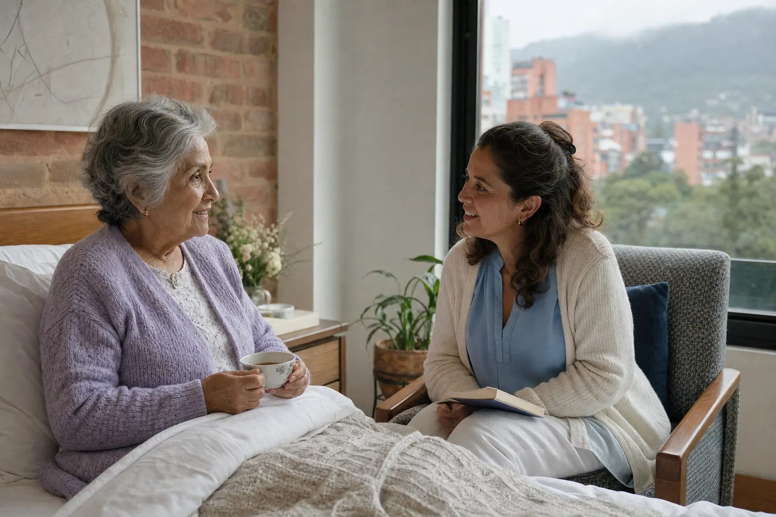 Cuidadora hospitalaria sentada junto a la cama de una persona mayor en una habitación de clínica en Bogotá