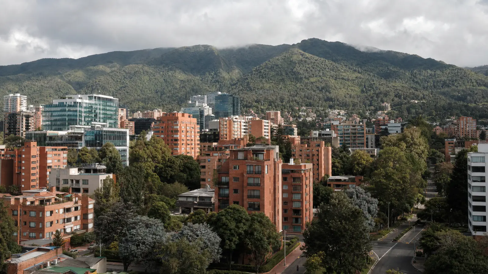 Calles arboladas y edificios residenciales del norte de Bogotá con los cerros orientales al fondo