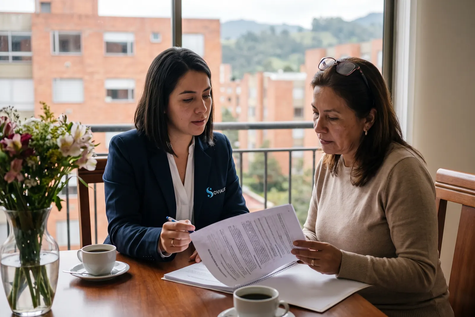 Coordinadora de Sovialis revisa con una hija adulta el plan de cuidado por escrito en la mesa del comedor